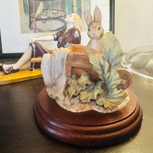 Beatrix Potter 'Peter Kanin' i en skottkärra på en träsockel