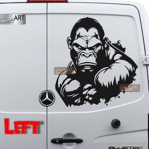 May include: Black and white gorilla sticker on a white van door. The sticker is of a gorilla with a serious expression, looking directly at the viewer. The sticker is on the left side of the van door. The word "LEFT" is printed in red below the sticker.