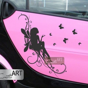 May include: A pink car with a black silhouette of a fairy with wings and a floral design on the side. The fairy is surrounded by small black butterflies.