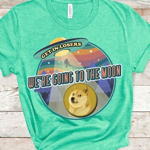 以下が含まれることがあります： 「Get in Losers, We're Going to the Moon」というテキストと柴犬の犬が描かれたレトロなUFOのグラフィックが施されたターコイズブルーのTシャツ。