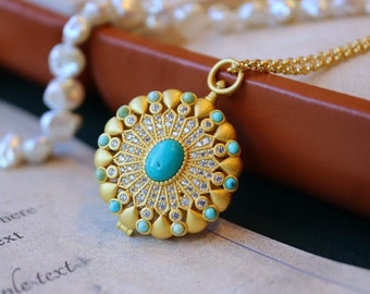 May include: A gold pendant necklace with a round turquoise stone surrounded by smaller stones. The pendant is attached to a gold chain.