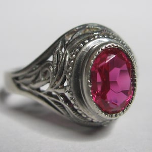 Puede incluir: Un anillo de plata con un diseño adornado y una gran piedra preciosa rosa de forma ovalada.