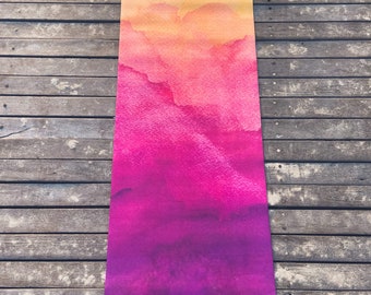 May include: A purple, pink, and yellow yoga mat with a watercolor design. The mat has the word "NIIDRA" printed on it in gold.