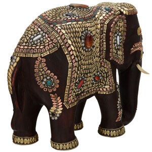 May include: A dark brown wooden elephant figurine with intricate gold and copper embellishments, including colorful gemstones. The elephant is decorated with paisley patterns and has a raised trunk.
