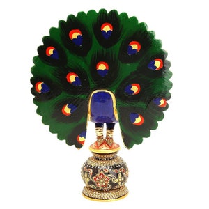 May include: A decorative peacock figurine with a vibrant green, blue, red, and gold color scheme. The peacock's tail feathers are spread, and the figurine is mounted on a detailed, ornate base. The figurine is made of wood.