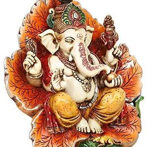 May include: A colorful, ornate statue of the Hindu deity Ganesha, depicted sitting on a lotus leaf. The statue is made of painted resin and features intricate details, including a crown, jewelry, and a trunk.