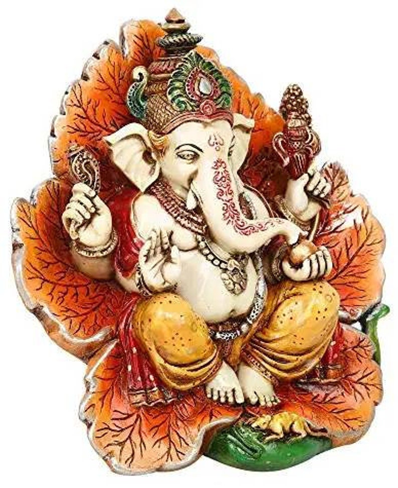 May include: A colorful, ornate statue of the Hindu deity Ganesha, depicted sitting on a lotus leaf. The statue is made of painted resin and features intricate details, including a crown, jewelry, and a trunk.