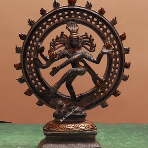 May include: A bronze statue of the Hindu deity Shiva Nataraja, the Lord of Dance. The statue depicts Shiva in a dynamic dancing pose within a circular frame. The statue has intricate details and a dark bronze finish with gold accents.