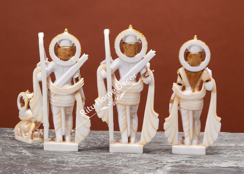 May include: Four white marble statues of Hindu deities with gold accents. The statues are standing and are arranged in a row. The statues are all facing the same direction. The statues are all wearing traditional Indian clothing.