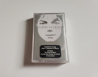 May include: A silver cassette tape of Michael Jackson's album "Invincible." The album cover features a grayscale image of Michael Jackson's face. The text on the cover includes the album title, song titles, and the number of songs.