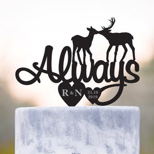 Könnte beinhalten: Schwarze Silhouette von zwei sich küssenden Rehen mit dem Wort "Always" in einer kursiv geschriebenen Schrift. Die Rehe stehen auf zwei Herzen mit den Initialen "R&N" und dem Datum "21.10.2019" auf den Herzen. Dies ist ein Hochzeitstortenaufsatz.
