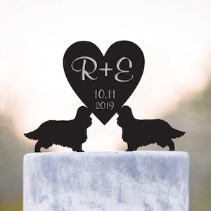 May include: Black silhouette cake topper featuring two Cavalier King Charles Spaniels facing each other with a heart-shaped topper above them. The heart topper has the initials "R+E" and the date "10.11.2019" inscribed on it.