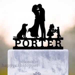 Puede incluir: Topper de pastel en silueta negra de una pareja besándose con un perro, un niño que sostiene un corazón con la fecha 10.14.2023 y un gato. El topper tiene el apellido "PORTER" escrito debajo de las figuras.