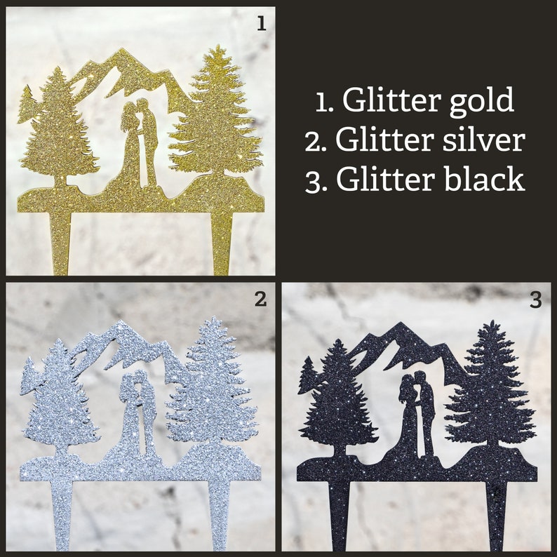 May include: A cake topper featuring a couple standing in front of a mountain range with two pine trees on either side. The topper is available in three colors: glitter gold, glitter silver, and glitter black.
