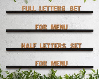 Op de afbeelding: Houten letters met de tekst "FULL LETTERS SET", "FOR MENU" en "HALF LETTERS SET" worden weergegeven op zwarte planken tegen een witte muur. Groen gebladerte omlijst de boven- en onderkant. De letters zijn lichtbruin.