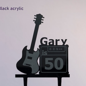 May include: Black acrylic cake topper featuring a silhouette of a guitar and amplifier with the text "Gary is 50".