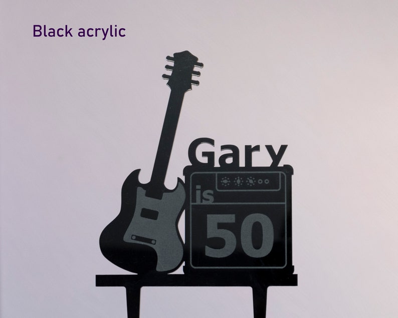 May include: Black acrylic cake topper featuring a silhouette of a guitar and amplifier with the text "Gary is 50".