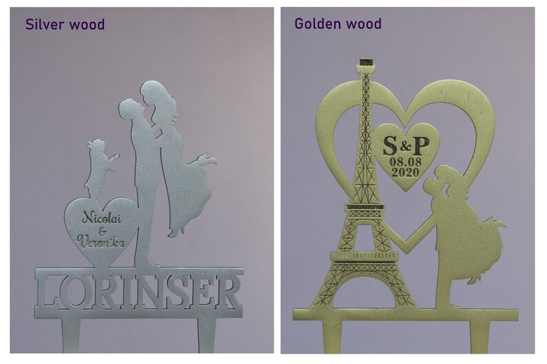 May include: Two wedding cake toppers, one silver and one gold. The silver topper features a couple kissing with a dog, a heart with the names "Nicolai & Veronika", and the word "LORINSER". The gold topper features a couple holding hands in front of the Eiffel Tower, a heart with the initials "S&P" and the date "08.08.2020".