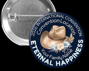 Puede incluir: Un botón redondo azul marino con el texto "2026 International Convention Location" y "Eternal Happiness". Presenta un sombrero de vaquero marrón y detalles florales. El botón tiene un respaldo de alfiler metálico.