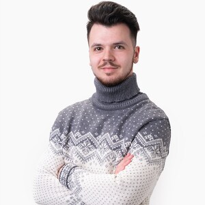 Peut inclure: Un pull &agrave; col roul&eacute; gris et blanc &agrave; motifs avec un design en jacquard. Le pull est pli&eacute; et pr&eacute;sent&eacute; sur un fond blanc.