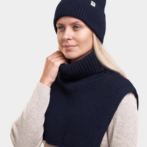 Può includere: Un berretto di lana blu navy e un collo a scaldacollo abbinato. Entrambi gli articoli presentano un piccolo logo bianco a forma di diamante.