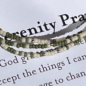 May include: A green and white beaded bracelet with the text "Serenity Prayer" and "God grant me the serenity to accept the things I cannot change" on a white background.