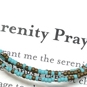May include: A turquoise and brown beaded bracelet with the text "Serenity Prayer" and the words "Grant me the serenity to accept the things I cannot change, the courage to change the things I can, and the wisdom to know the difference."