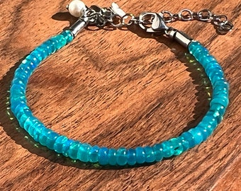 May include: A turquoise opal beaded bracelet with a silver clasp and a pearl charm.