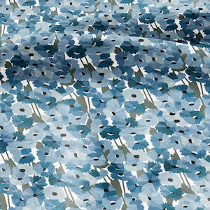 Pode incluir: Close-up de um tecido com um padrão floral. O design apresenta numerosas flores azuis com centros escuros e caules verdes sobre um fundo branco. As flores variam em tons de azul, criando uma aparência texturizada.