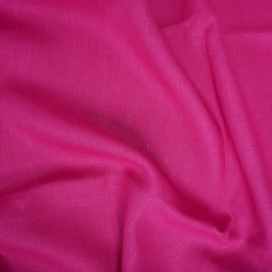 May include: A close-up of a vibrant pink fabric with a textured linen weave. The fabric is draped and folded, creating soft, flowing lines.