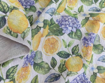 May include: White linen fabric with a repeating pattern of yellow lemons, green leaves, and purple hydrangeas.