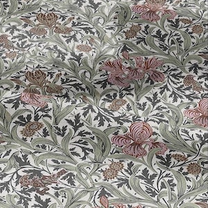 May include: A close-up of a floral pattern with irises, leaves, and birds in brown, pink, and green on a cream background. The design is reminiscent of vintage botanical illustrations, suitable for fabric or wallpaper.