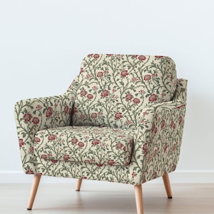 Puede incluir: Un sillón crema con un estampado floral de flores rojas y vides verdes. La silla tiene respaldo cuadrado, reposabrazos y patas de madera clara. El diseño floral cubre toda la silla.