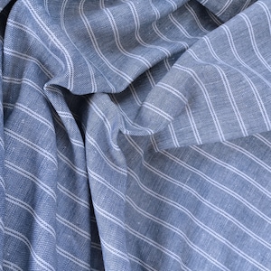 May include: Blue and white striped fabric with a textured weave. The fabric is folded and draped, showing the diagonal stripes.
