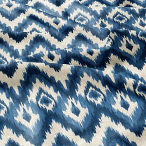 Könnte beinhalten: Nahaufnahme eines Stoffes mit einem blau-weißen Ikat-Muster. Das Design zeigt ein sich wiederholendes Zickzackmuster mit rautenförmigen Elementen. Der Stoff hat ein strukturiertes Aussehen mit sichtbaren Falten und Knicken.
