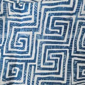 May include: Close-up of a fabric with a repeating geometric pattern in shades of blue and white. The design features a maze-like motif, creating a textured and visually engaging surface. The fabric appears to be linen or a similar natural fibre.