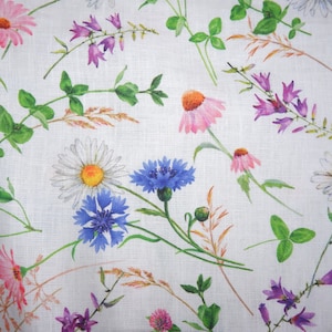 Pode incluir: Um tecido branco com um padrão floral que apresenta flores rosa, brancas, azuis e roxas. As flores estão dispostas em um padrão aleatório e são cercadas por folhas verdes.