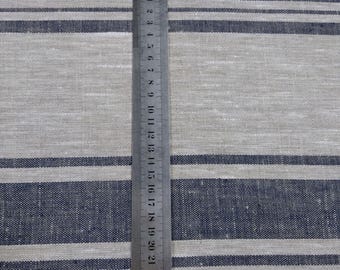 Puede incluir: Primer plano de una tela de lino natural con rayas azules. Una regla se coloca verticalmente a lo largo de la tela, mostrando la medida en pulgadas.