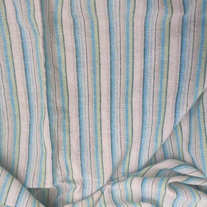 以下が含まれることがあります： 青、緑、ピンクのストライプの生地のクローズアップ。生地はしわくちゃで、柔らかく、質感があります。