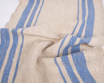 Puede incluir: Una tela de lino natural con rayas azules. La tela está doblada y tiene textura.