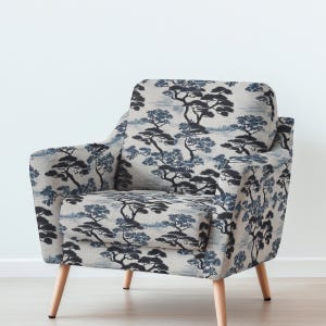 May include: An armchair with a light-colored fabric featuring a repeating pattern of stylized dark blue and black trees. The chair has a rounded back and armrests, with light wooden legs. The overall design is reminiscent of a Japanese landscape.