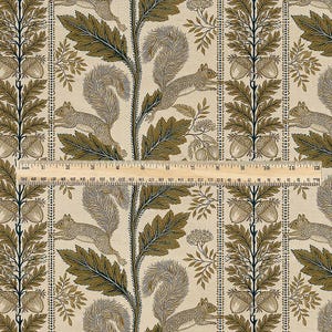 May include: A beige fabric featuring a repeating pattern of brown squirrels, oak leaves, and acorns, with a wooden ruler placed horizontally across the center showing a measurement of 12 inches in length for scale and reference.