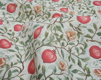 May include: A white fabric with a repeating pattern of red pomegranates and green leaves. The fabric has a subtle texture.
