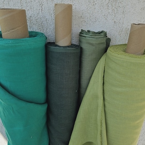 May include: Four rolls of fabric in different shades of green. The fabric is a linen blend and has a subtle texture. The rolls are arranged side by side, with the darkest green roll on the left and the lightest green roll on the right.
