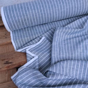 May include: A roll of blue and white striped fabric. The fabric is folded and has a white fringe.