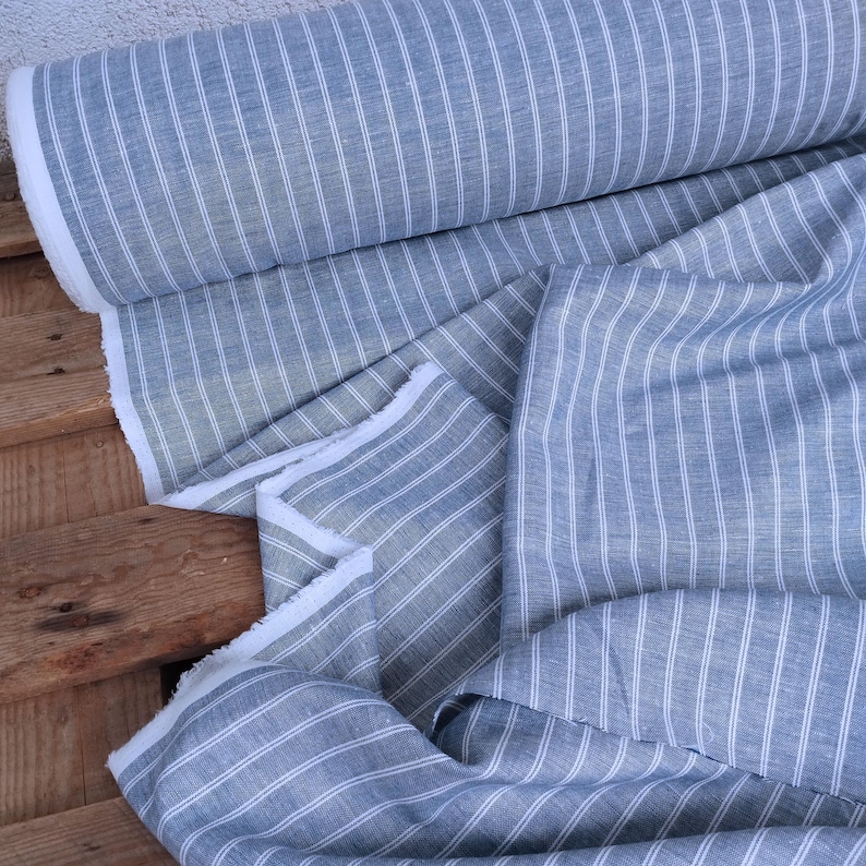 May include: A roll of blue and white striped fabric. The fabric is folded and has a white fringe.