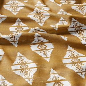 Pode incluir: Um close-up de um tecido com um padrão repetitivo de formas de diamantes brancas sobre um fundo amarelo mostarda. O tecido tem uma textura sutil.