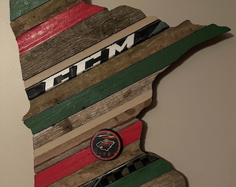 Pode incluir: Um contorno de madeira do estado de Minnesota com um taco de hóquei e um logotipo do Minnesota Wild. O contorno é feito de várias tábuas de madeira em tons de verde, vermelho e marrom.
