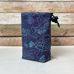 May include: A dark purple drawstring bag with a blue and white mushroom print. The bag has a black drawstring and a black toggle.