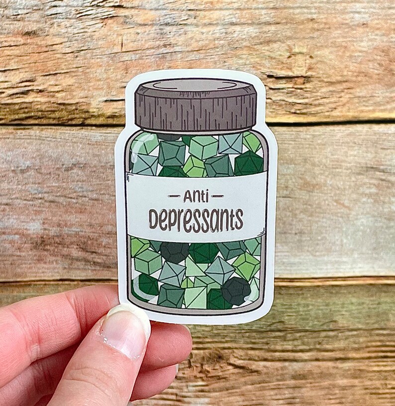 May include: A sticker featuring a jar of "Anti-Depressants." The jar is filled with green geometric shapes. The label on the jar reads "Anti-Depressants" in a bold, sans-serif font. The jar has a gray lid and is outlined in black.